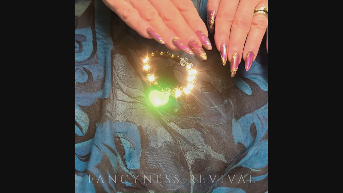 Load video: hands giving reiki to a bracelet with sparkles in the background