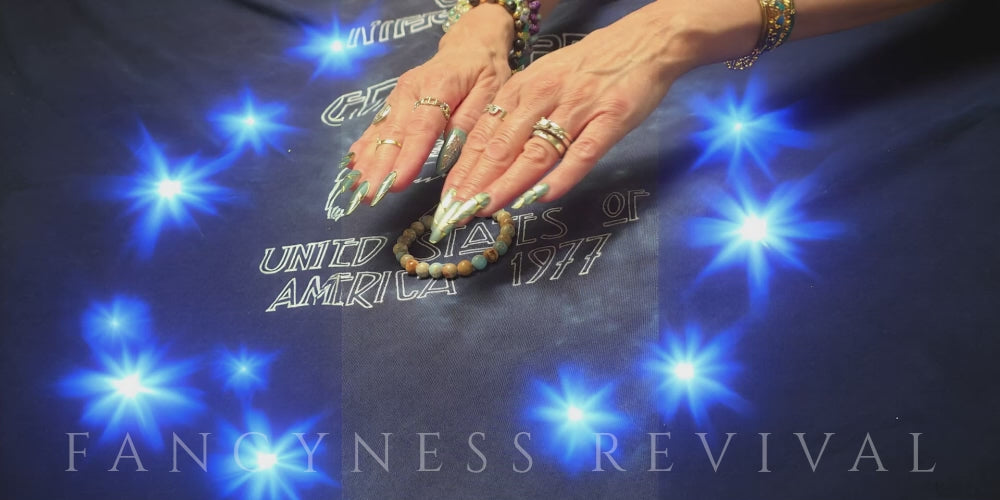 Load video: hands giving reiki to a bracelet with sparkles in the background