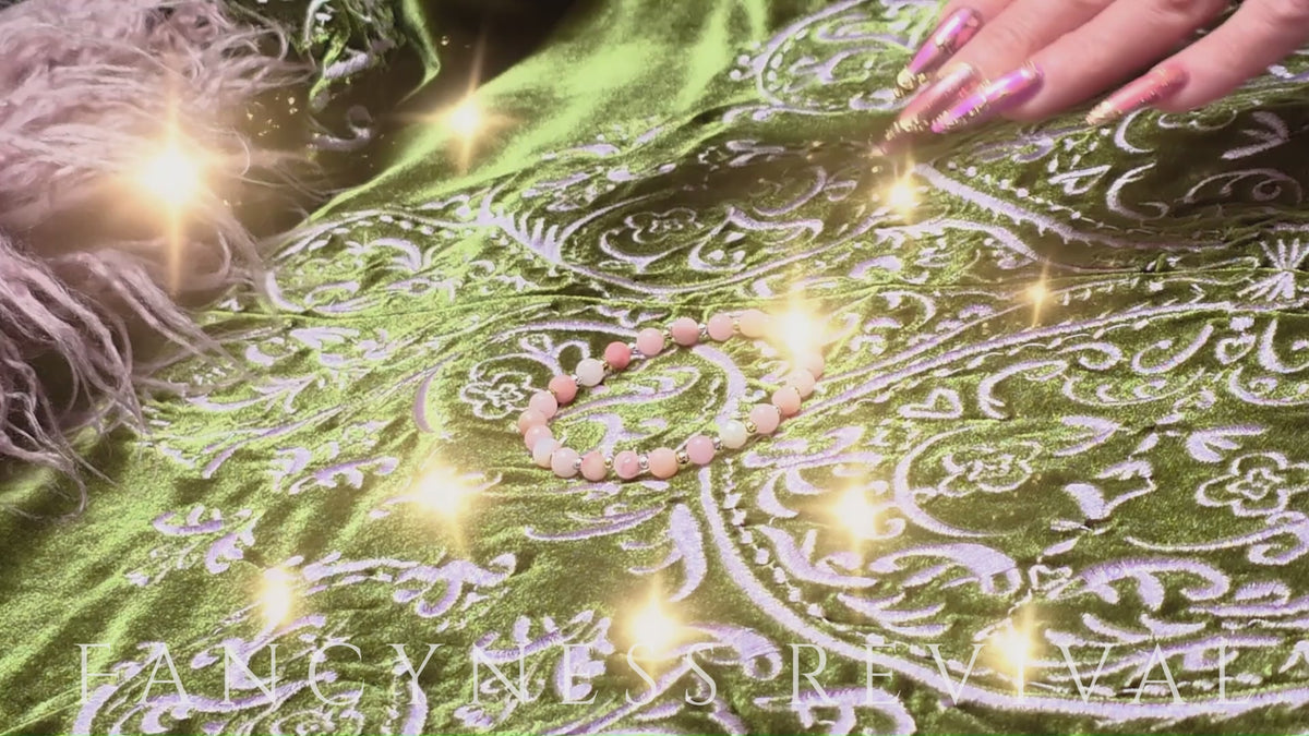 Load video: hands giving reiki to a bracelet with sparkles in the background