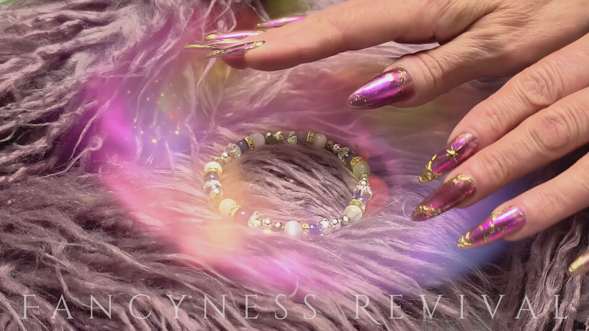Load video: hands giving reiki to a bracelet with sparkles in the background
